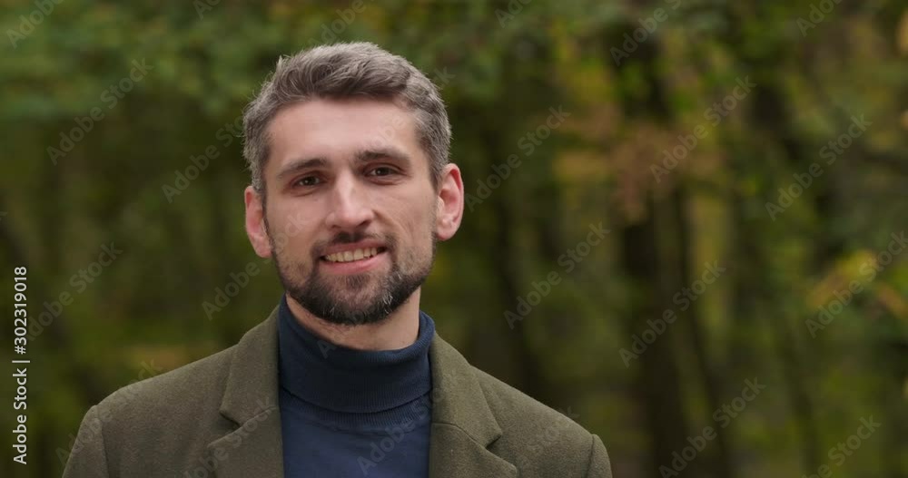 Close-up face of smiling handsome gray-haired Caucasian man with brown eyes standing in forest and smiling. Male tourist enjoying calm quiet autumn day alone. Cinema 4k footage ProRes HQ. Close-up face of smiling handsome gray-haired Caucasian man with brown eyes standing in forest and smiling. Male tourist enjoying calm quiet autumn day alone. Cinema 4k footage ProRes HQ.