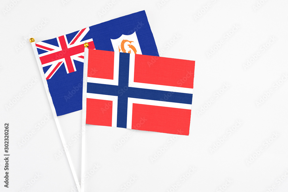 Fototapeta premium Bouvet Islands and Anguilla stick flags on white background. High quality fabric, miniature national flag. Peaceful global concept.White floor for copy space.