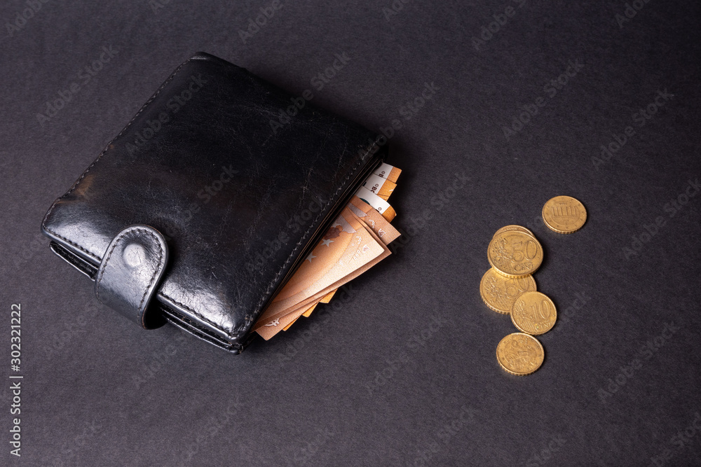 leather wallet with a pile of euro banknotes and euro money cash coins, finance currency isolated, dark background. coins and banknotes 100 and 50 euros in a man's leather purse. Top view Men's wallet leather wallet with a pile of euro banknotes and euro money cash coins, finance currency isolated, dark background. coins and banknotes 100 and 50 euros in a man's leather purse. Top view Men's wallet