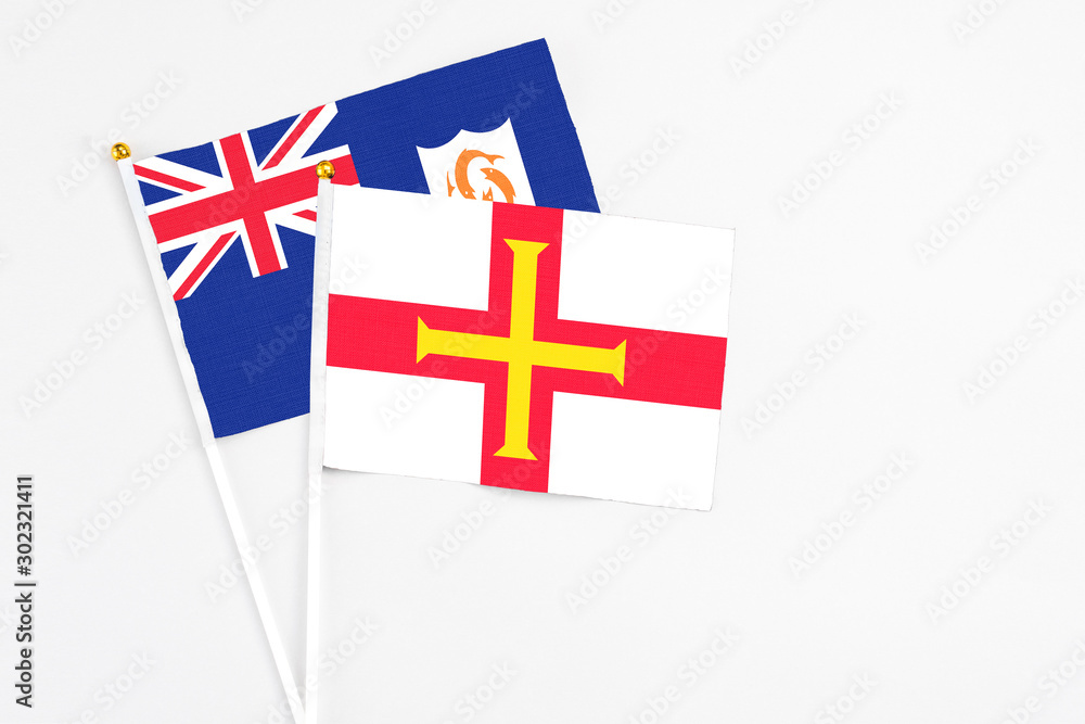 Guernsey and Anguilla stick flags on white background. High quality fabric, miniature national flag. Peaceful global concept.White floor for copy space.
