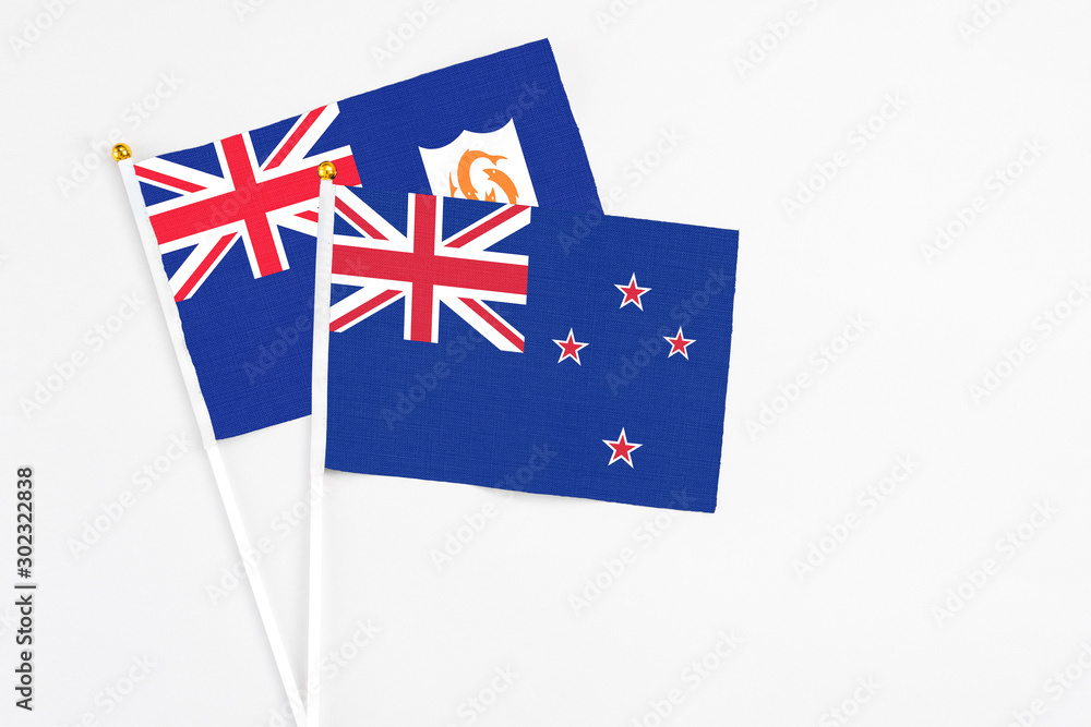Fototapeta premium New Zealand and Anguilla stick flags on white background. High quality fabric, miniature national flag. Peaceful global concept.White floor for copy space.