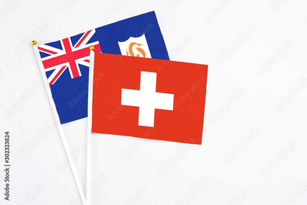 Switzerland and Anguilla stick flags on white background. High quality fabric, miniature national flag. Peaceful global concept.White floor for copy space.