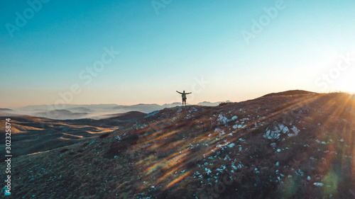 Winner silhouette on the mountain top. Sport and active life concept. Sunset behind.