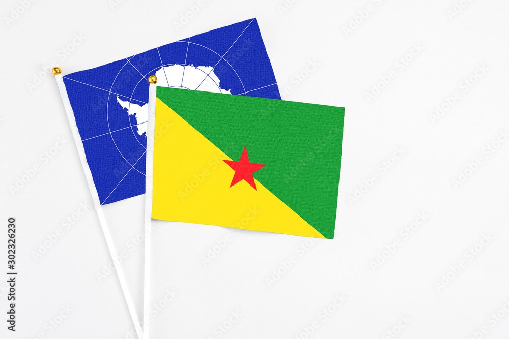 French Guiana and Antarctica stick flags on white background. High quality fabric, miniature national flag. Peaceful global concept.White floor for copy space.