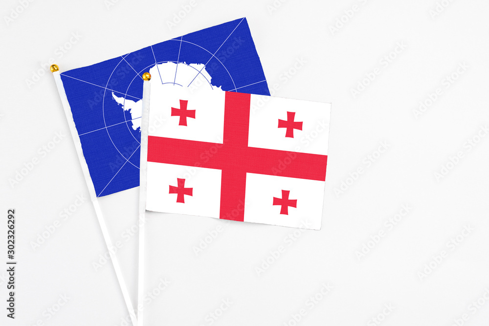 Georgia and Antarctica stick flags on white background. High quality fabric, miniature national flag. Peaceful global concept.White floor for copy space.