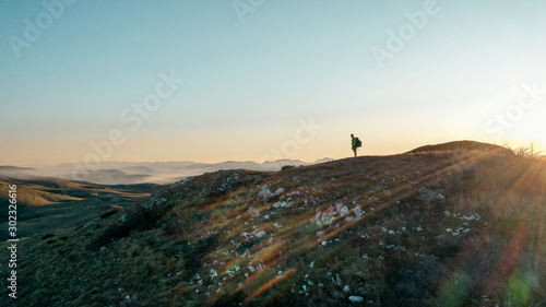 Winner silhouette on the mountain top. Sport and active life concept. Sunset behind.