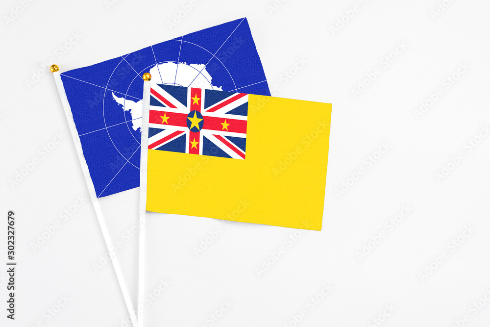 Niue and Antarctica stick flags on white background. High quality fabric, miniature national flag. Peaceful global concept.White floor for copy space. Niue and Antarctica stick flags on white background. High quality fabric, miniature national flag. Peaceful global concept.White floor for copy space.