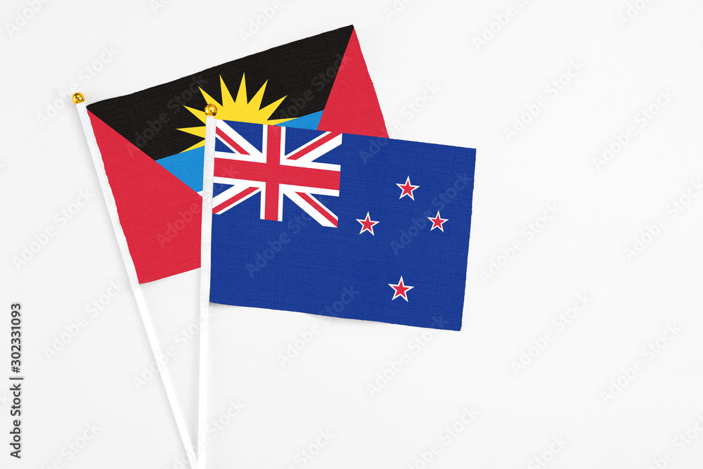 Fototapeta premium New Zealand and Antigua and Barbuda stick flags on white background. High quality fabric, miniature national flag. Peaceful global concept.White floor for copy space.