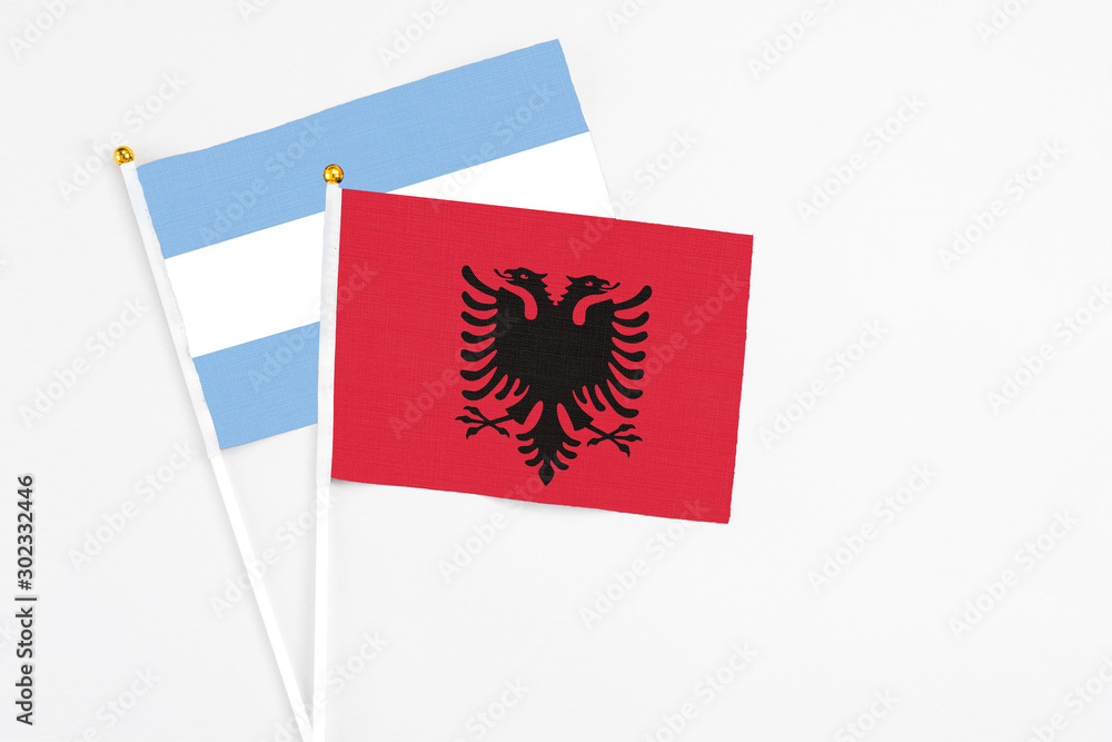 Obraz premium Albania and Argentina stick flags on white background. High quality fabric, miniature national flag. Peaceful global concept.White floor for copy space.