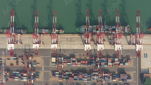 Overhead drone shot of cranes and cargo vessels in Port of Qingdao in China photo