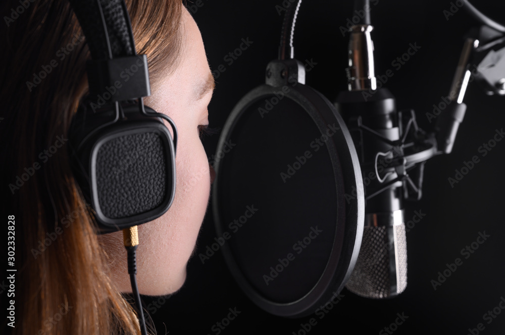 Female vocal recording. Young girl with microphone and headphones in