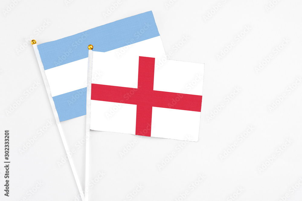 England and Argentina stick flags on white background. High quality fabric, miniature national flag. Peaceful global concept.White floor for copy space.