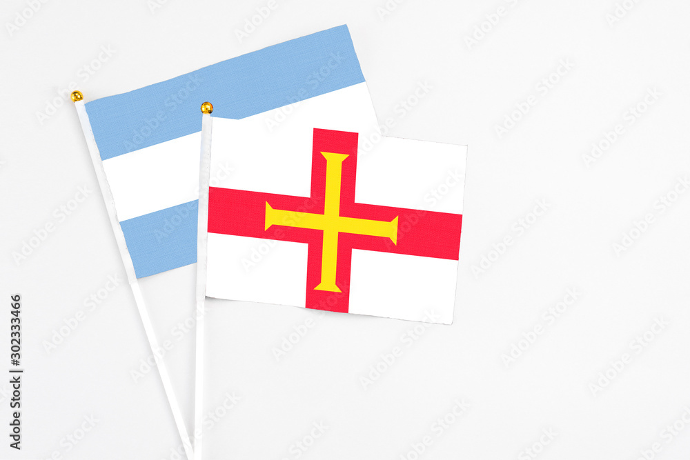 Guernsey and Argentina stick flags on white background. High quality fabric, miniature national flag. Peaceful global concept.White floor for copy space.