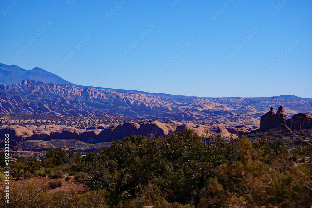A desert landscape view with some sandstone hills and mountains in the distance