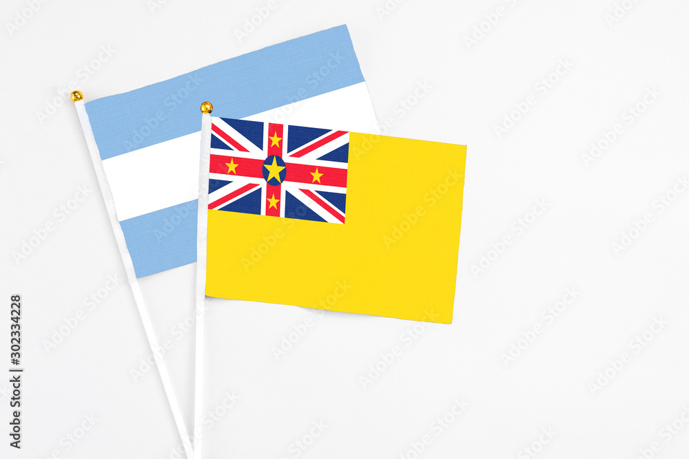 Niue and Argentina stick flags on white background. High quality fabric, miniature national flag. Peaceful global concept.White floor for copy space. Niue and Argentina stick flags on white background. High quality fabric, miniature national flag. Peaceful global concept.White floor for copy space.