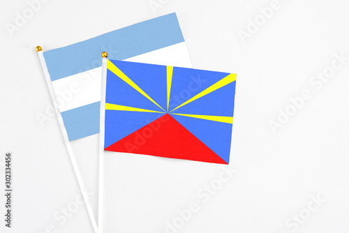 Reunion and Argentina stick flags on white background. High quality fabric, miniature national flag. Peaceful global concept.White floor for copy space.