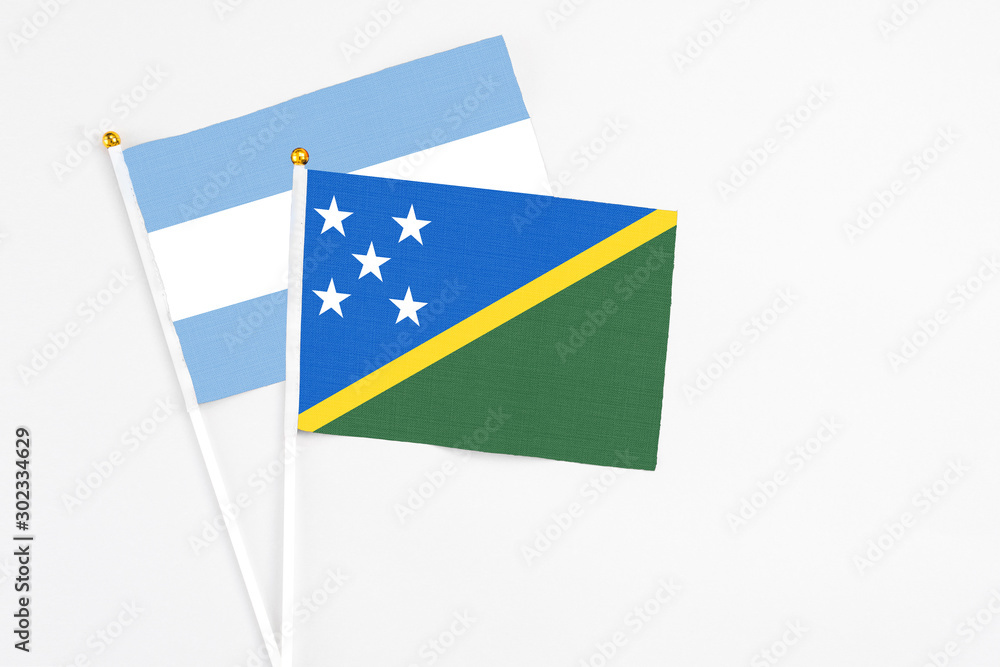 Solomon Islands and Argentina stick flags on white background. High quality fabric, miniature national flag. Peaceful global concept.White floor for copy space. Solomon Islands and Argentina stick flags on white background. High quality fabric, miniature national flag. Peaceful global concept.White floor for copy space.