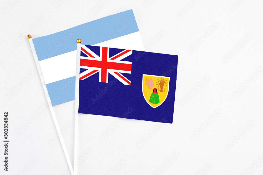 Fototapeta premium Turks And Caicos Islands and Argentina stick flags on white background. High quality fabric, miniature national flag. Peaceful global concept.White floor for copy space.