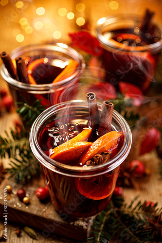 Christmas mulled red wine with aromatic spices and citrus fruits on a wooden rustic table, close-up. Traditional hot drink at Christmas time