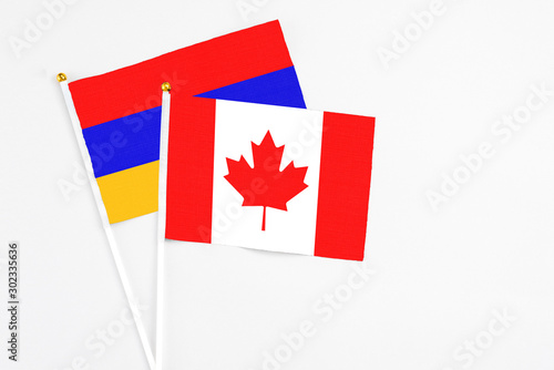 Canada and Armenia stick flags on white background. High quality fabric, miniature national flag. Peaceful global concept.White floor for copy space.