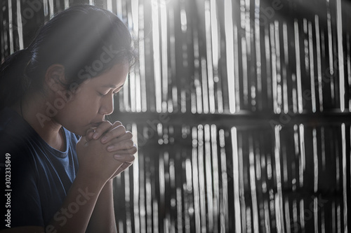 Girl while praying for christian religion with blurred of her body background.