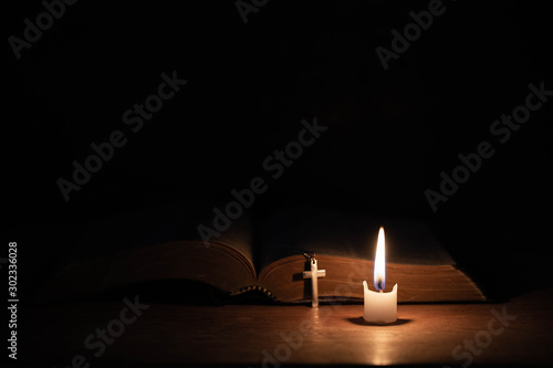 Cross with bible and candle on a old oak wooden table. photo