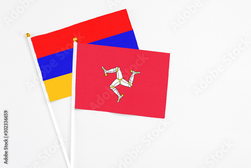Isle Of Man and Armenia stick flags on white background. High quality fabric, miniature national flag. Peaceful global concept.White floor for copy space.