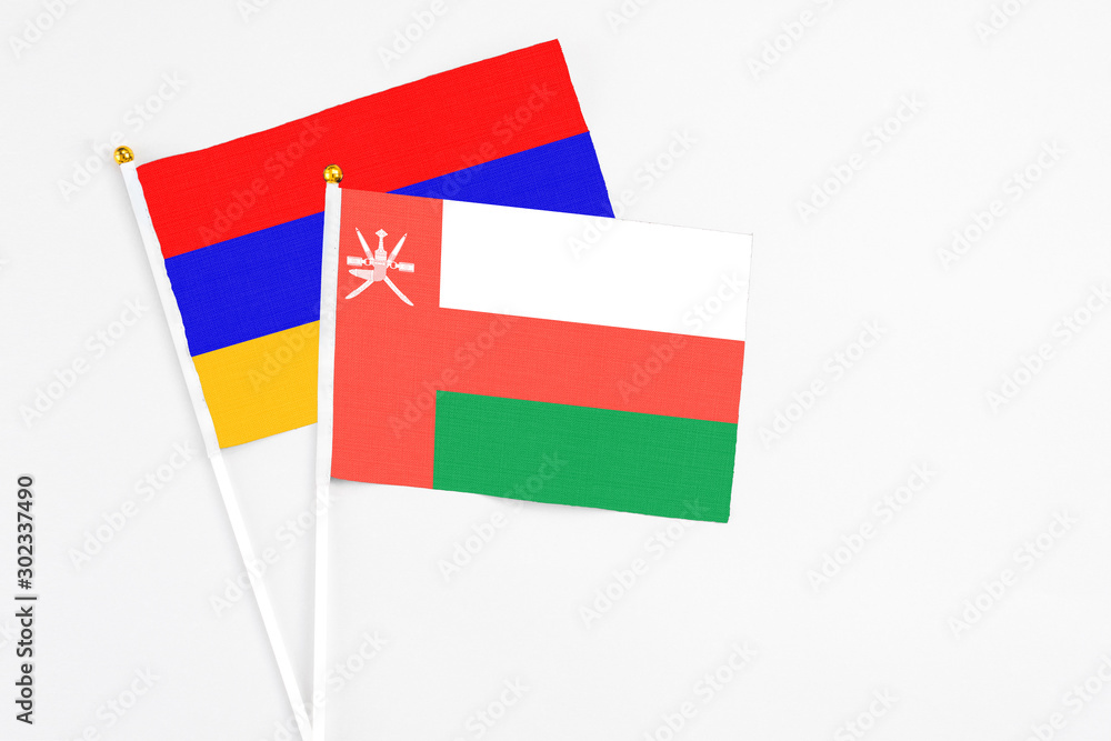 Obraz premium Oman and Armenia stick flags on white background. High quality fabric, miniature national flag. Peaceful global concept.White floor for copy space.