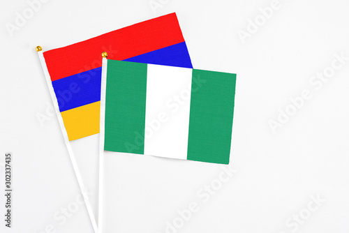 Nigeria and Armenia stick flags on white background. High quality fabric, miniature national flag. Peaceful global concept.White floor for copy space.