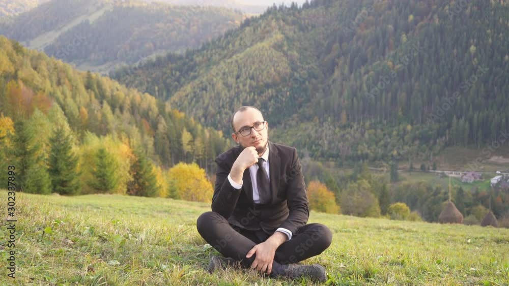 Man In A Nice Suit Meditates While Sitting On The Hill Man In A Nice Suit Meditates While Sitting On The Hill
