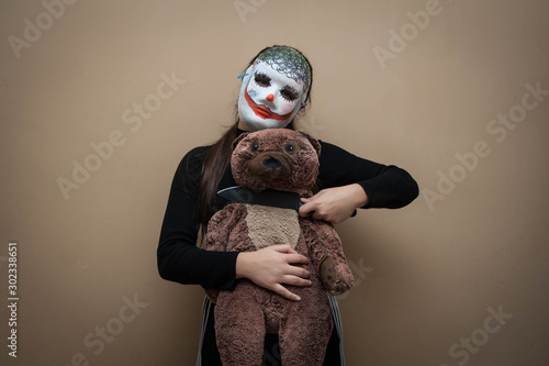 Masked man holds a knife to the throat of a Teddy bear. Kids violence. Child abuse