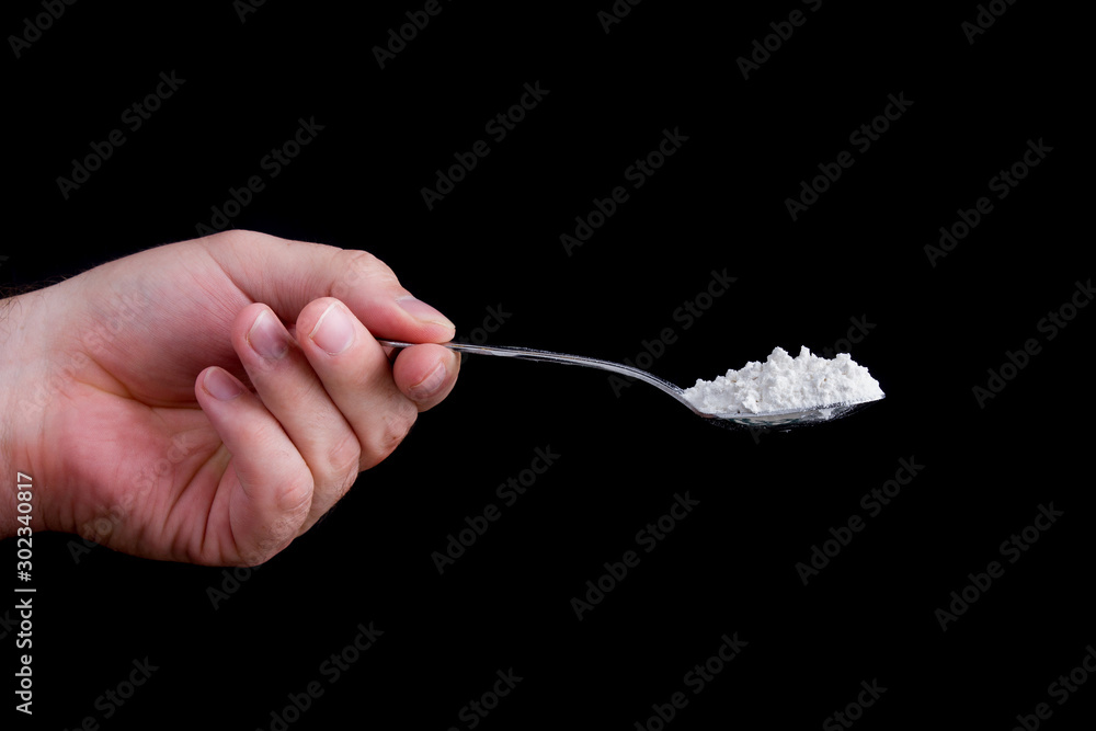 Fototapeta premium Hand holding a spoon full of a white powder