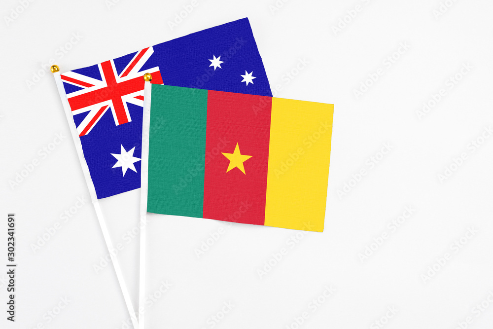 Cameroon and Australia stick flags on white background. High quality fabric, miniature national flag. Peaceful global concept.White floor for copy space.