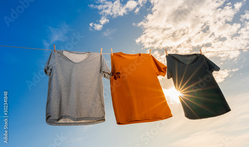 Quadro su tela laundry concept of three dry t-shirts hanging on a clothesline with the sun shin