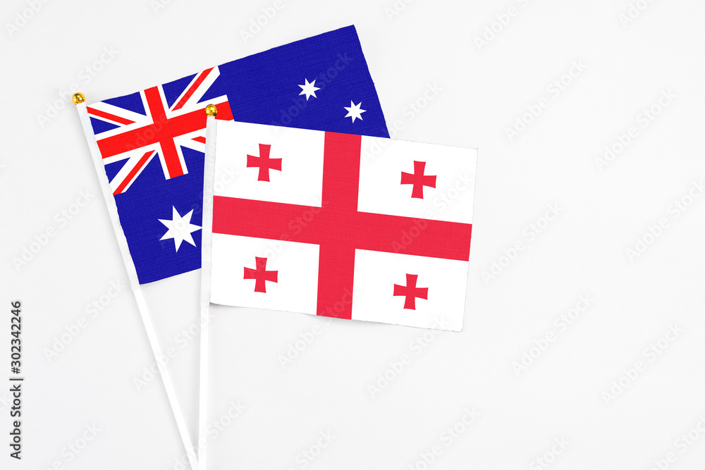 Georgia and Australia stick flags on white background. High quality fabric, miniature national flag. Peaceful global concept.White floor for copy space.