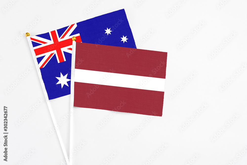 Latvia and Australia stick flags on white background. High quality fabric, miniature national flag. Peaceful global concept.White floor for copy space.
