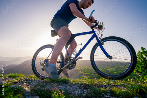 Close up photo from a mountain biker riding his bike ( bicycle) on rough rocky terrain on top of a mountain, wearing no safety equipment. Adrenalin junkie. © qunica.com