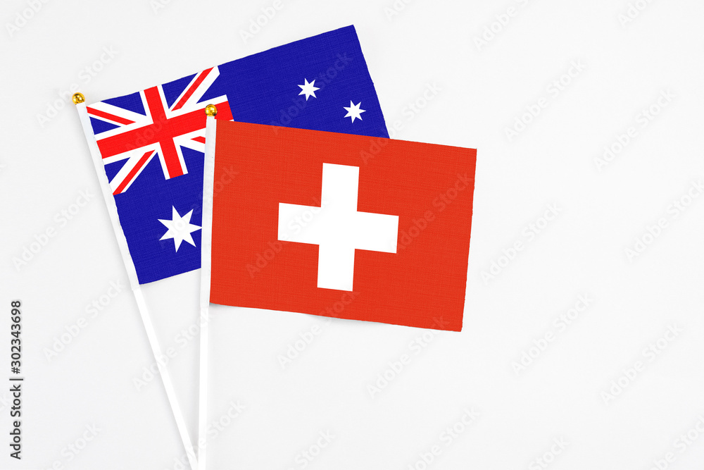 Switzerland and Australia stick flags on white background. High quality fabric, miniature national flag. Peaceful global concept.White floor for copy space.