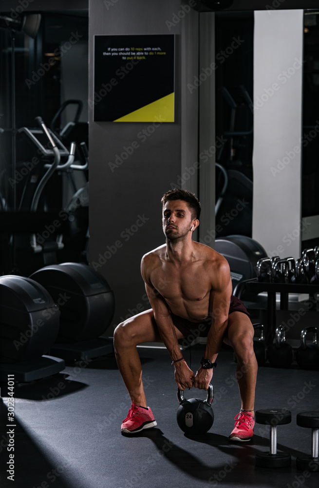 Slim muscular man lifting weights in the gym Slim muscular man lifting weights in the gym