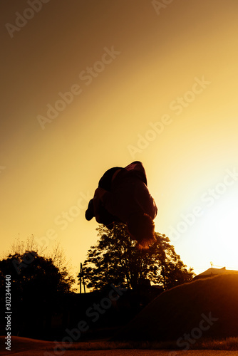 Young silhouette man performing a back flip