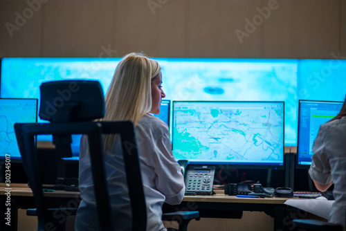 Female security guards working in surveillance room, monitoring cctv and discussing.