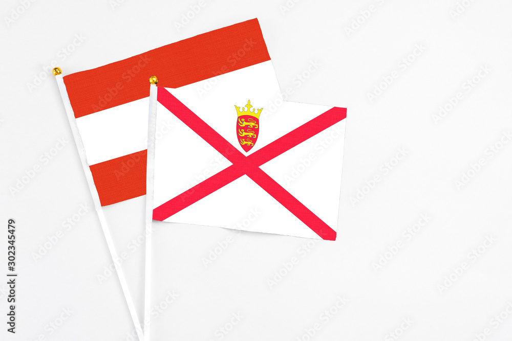 Fototapeta premium Jersey and Austria stick flags on white background. High quality fabric, miniature national flag. Peaceful global concept.White floor for copy space.