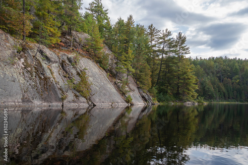 Smooth rock slope with trees reflected in still water