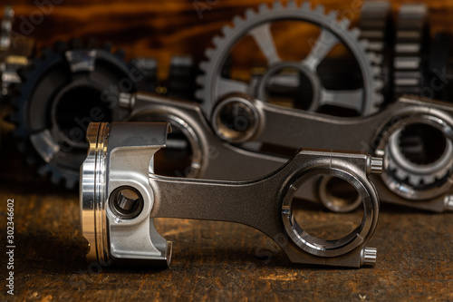 high performance racing motorcycle piston and Conrods on a workbench with gears in the background. 