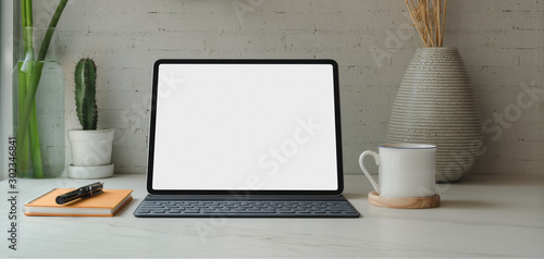 Close-up view of blank screen digital tablet with books and office supplies with coffee cup