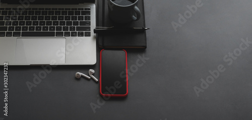 Overhead shot of laptop computer and smartphone with copy space on black table