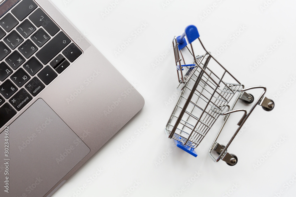 Creative promotion composition for online shopping sale on white background with laptop and grocery cart. Flat lay, top view, overhead, mockup, template
