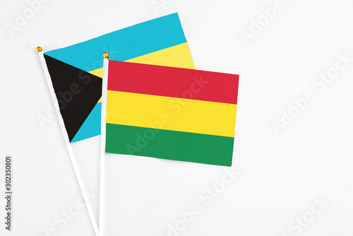 Bolivia and Bahamas stick flags on white background. High quality fabric  miniature national flag. Peaceful global concept.White floor for copy space.
