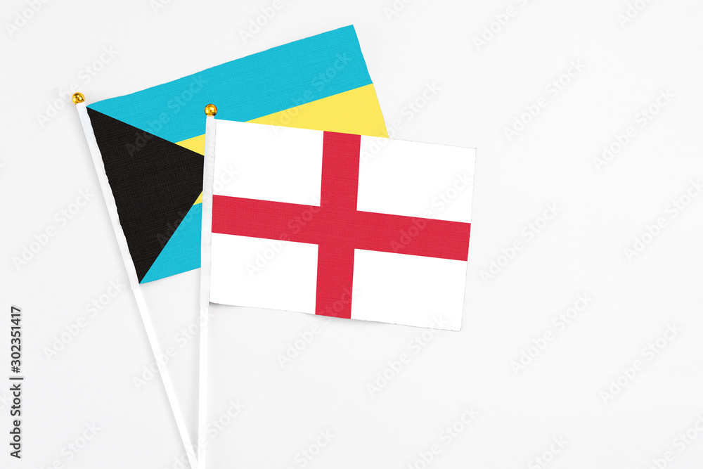 England and Bahamas stick flags on white background. High quality fabric, miniature national flag. Peaceful global concept.White floor for copy space.