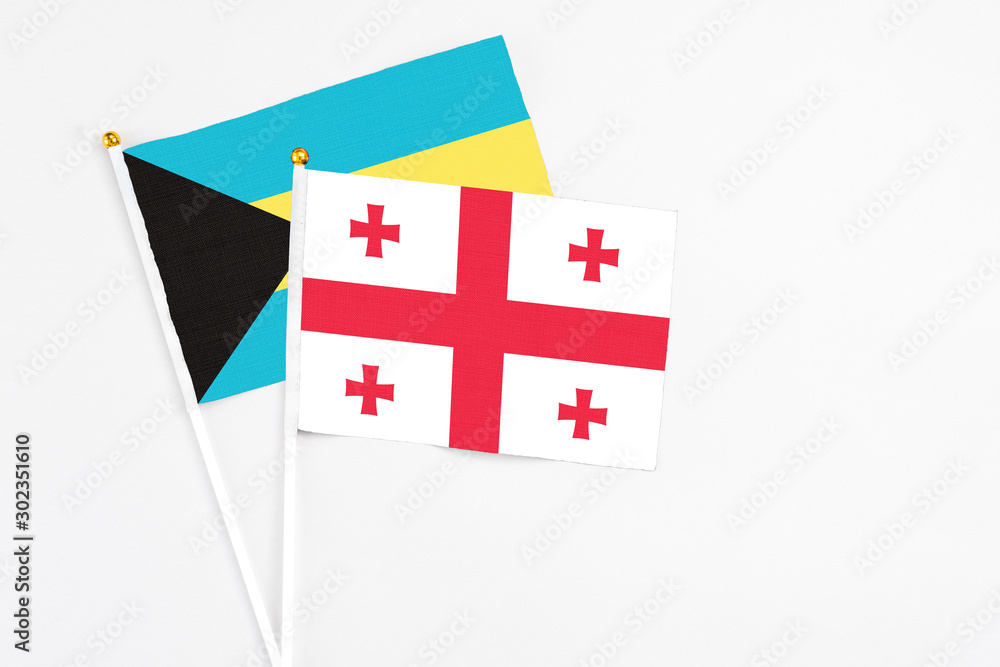 Georgia and Bahamas stick flags on white background. High quality fabric, miniature national flag. Peaceful global concept.White floor for copy space.